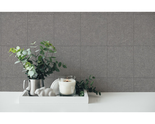 Decoratieve opstelling met behang met patroon, kaars en groene planten op een tafel