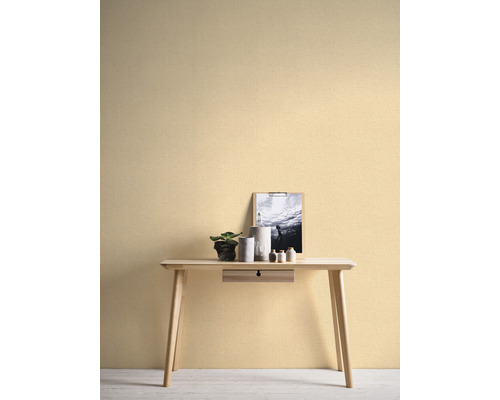 Decoratieve wand met licht vliesbehang, bureau, plant en decoraties.