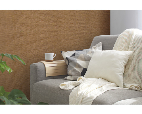 Woonkamer met bruin structuurbehang, bank, kussens en plant