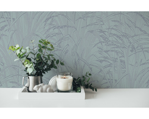 Close-up van een wand met botanisch behang, een dienblad met decoraties en een vaas met eucalyptus.