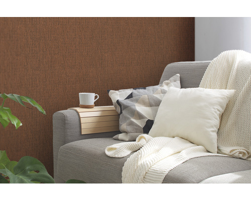 Woonkamer met bruin structuurbehang, grijze bank, kussens en bekerhouder