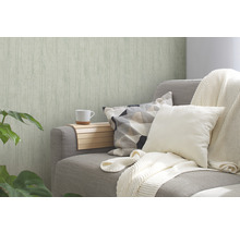 Woonkamer met patroonbehang, bank met kussens en sprei