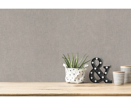 Close-up van een beige textielbehang met decoratieve elementen op een houten tafel