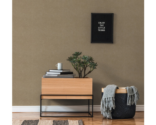 Close-up van een kamer met patroonbehang, houten tafel met plant, stapel boeken en mand met deken