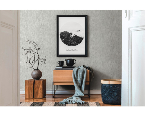 Woonkamer met patroonbehang, houten ladekast en decoratieve elementen