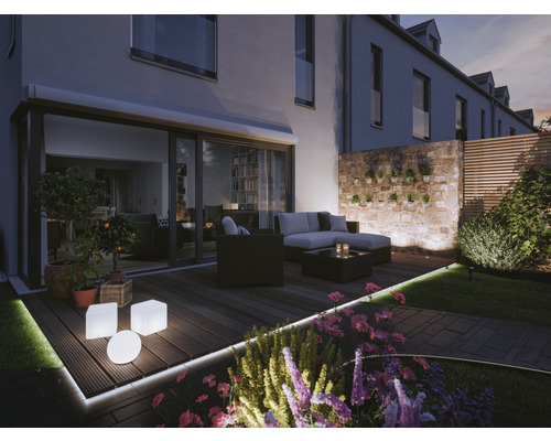 Terras met tuinmeubelen, verlichting en planten in de schemering