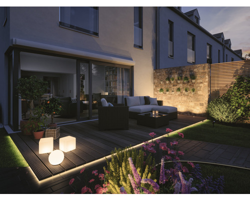 Verlicht terras met tuinmeubelen, plantenbakken en decoratieve verlichting.