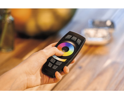 Een hand houdt een afstandsbediening vast om de verlichting te bedienen.