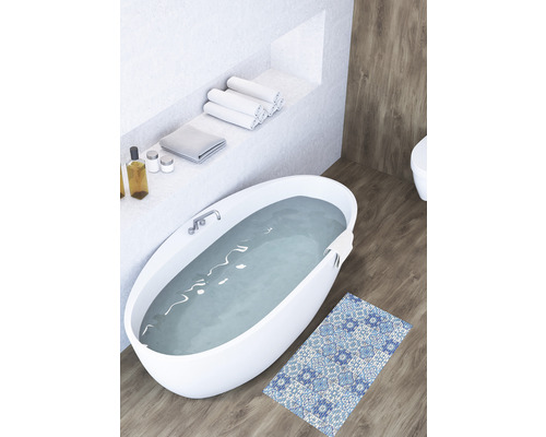 Badkamer met vrijstaand bad, handdoeken en een badmat met patroon op een houten vloer