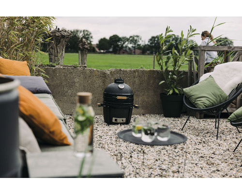 Tuinscene met keramische grill, zitmeubelen en planten