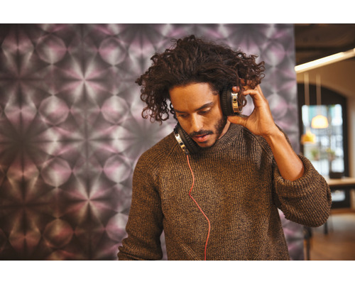 Een man met een hoofdtelefoon voor een wand met patroon