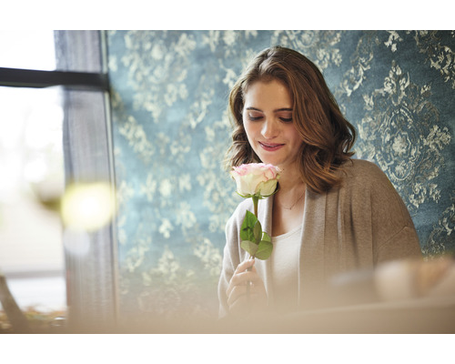 Vrouw houdt roos vast voor een behang met patroon