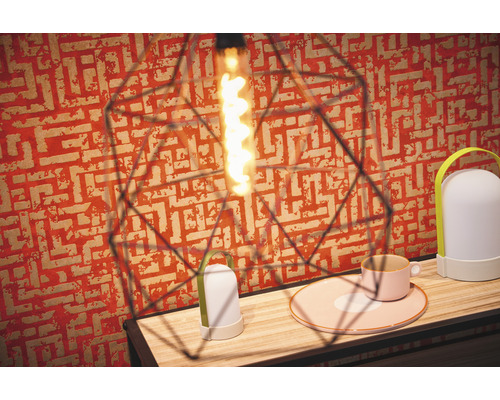 Interieurfoto met decoratieve lamp, tafellamp en servies op een houten tafel voor een behang met patroon