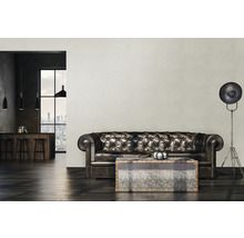 Woonkamer met leren bank, salontafel en staande lamp voor een patroonbehang