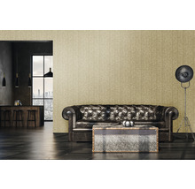 Woonkamer met bruine leren bank, salontafel, staande lamp en behang met motief