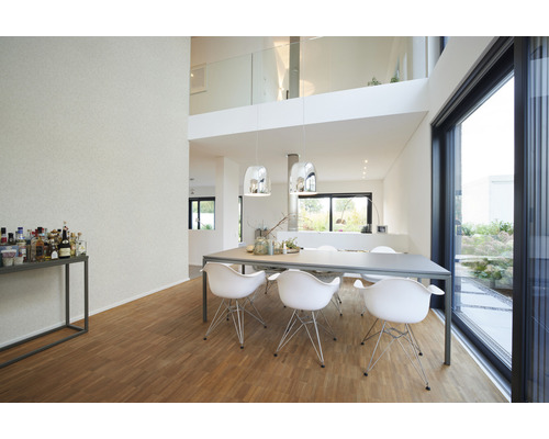 Lichte eetkamer met eettafel, stoelen, verlichting en uitzicht op de tuin.