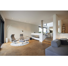 Lichte woonkamer met open haard, fauteuils, booglamp en houten vloer