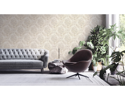 Woonkamer met patroonbehang, bank, fauteuil en kamerplanten.