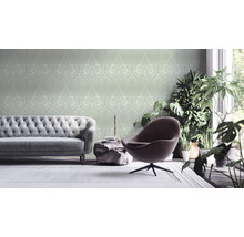 Woonkamer met bank, fauteuil, kamerplanten en behang met patroon