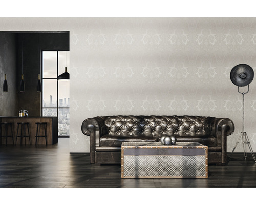 Woonkamer met leren bank, patroonbehang en staande lamp