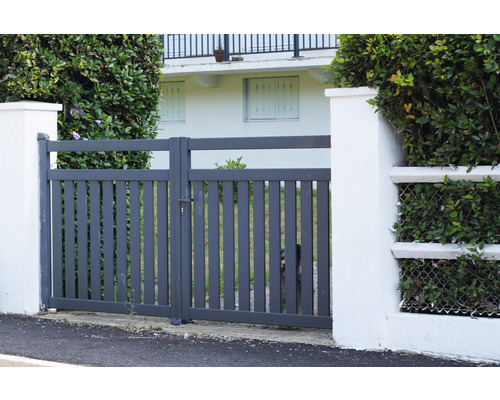 Grijze metalen tuinpoort tussen twee witte pilaren