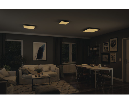 Woonkamer met bank, eettafel en vierkante plafondlampen voor een heldere en uitnodigende sfeer.