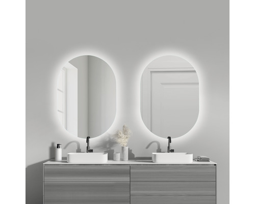 Badkamer met dubbele wastafel, twee verlichte spiegels en grijze onderkasten.