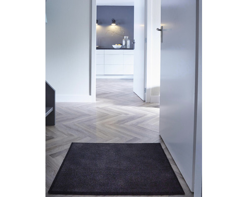 Hal met deurmat, houten vloer en zicht op de keuken