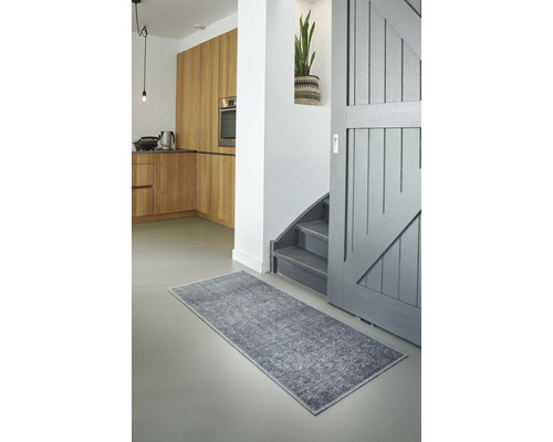 Hal met grijs tapijt, trap en houten keuken