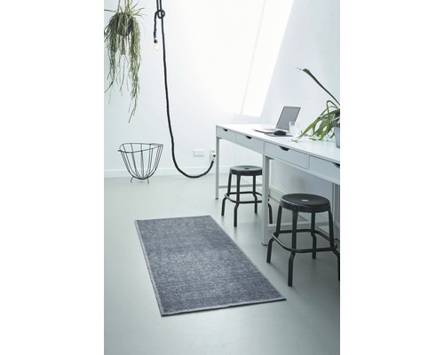 Een lichte kamer met een grijs vloerkleed, een wit bureau en twee krukken