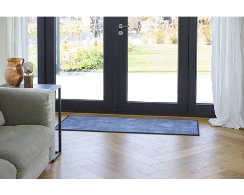 Scene met een deurmat voor een terrasdeur, een bank en een bijzettafel