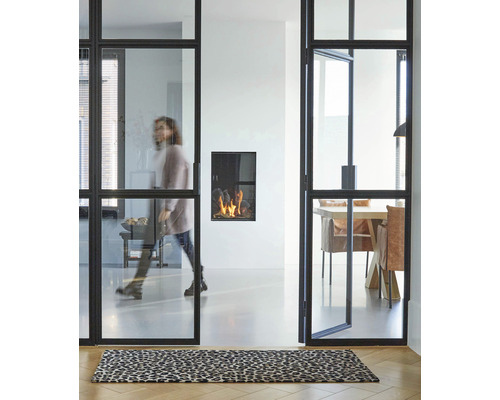 Lichte kamer met zwart glazen deursysteem, open haard en tapijt met dierenprint