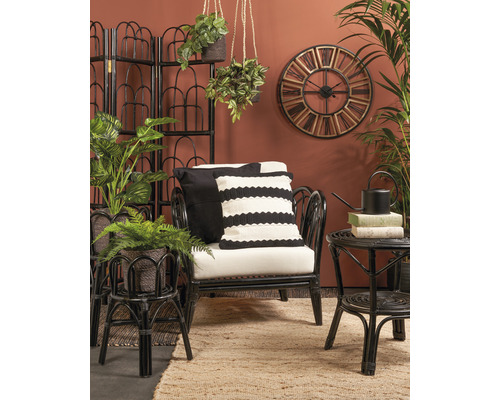 Woonkamer met rotan stoel, bijzettafel, kamerscherm, wandklok en kamerplanten voor een gezellige sfeer