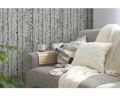 Woonkamer met grijze bank, kussens, deken en behang met berkenmotief