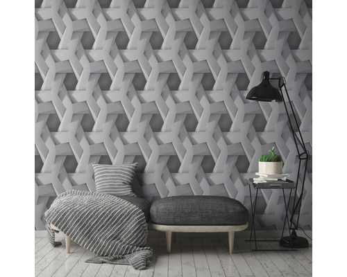 Woonkamer met wandbekleding met geometrisch 3D-effect, een fauteuil, een hocker en een vloerlamp.