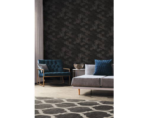 Woonkamer met een bank, een fauteuil en een wand met zeshoekige panelen