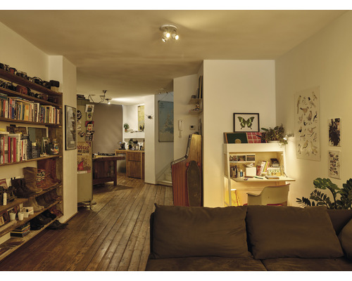 Woonkamer met boekenkast, bureau en plafondlamp