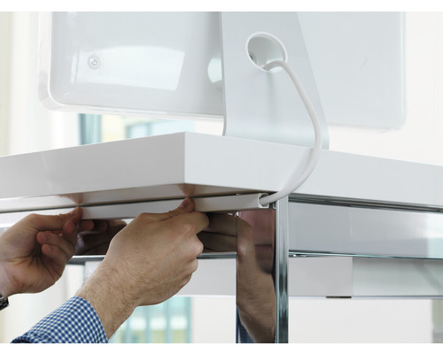 Persoon bevestigt een kabelgoot aan een bureau voor kabelbeheer.