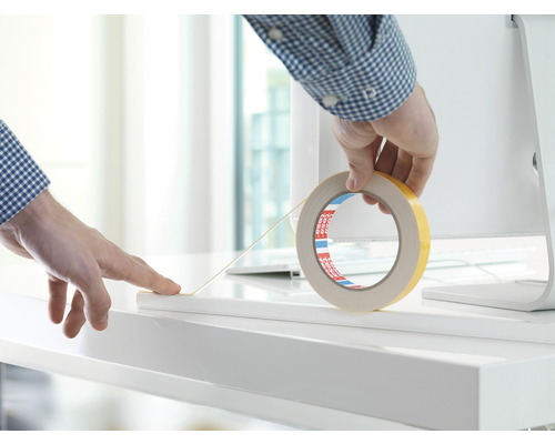 Dubbelzijdige tape wordt op een wit oppervlak aangebracht.