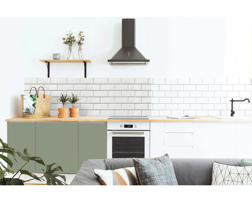 Moderne keuken met witte metrotegels, groene en witte kasten, afzuigkap en houten elementen.