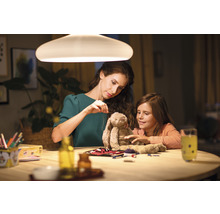 Vrouw en kind naaien een knuffel onder een lamp aan tafel