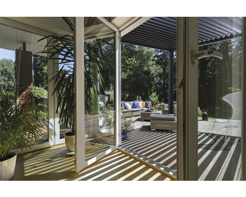 Doorkijk door een glazen deur naar een terras met tuinmeubelen en een pergola