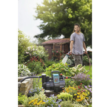 Tuin met hydrofoorpomp en persoon die water geeft met een slang