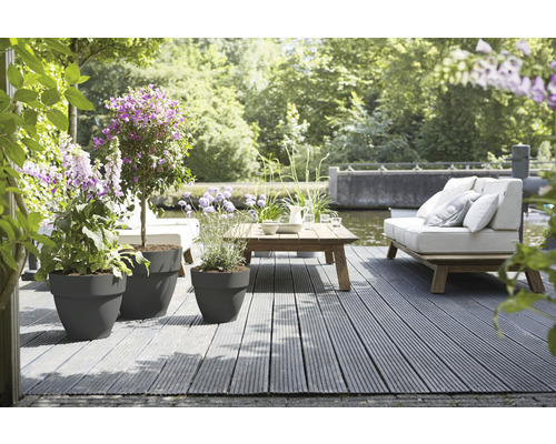 Terras met plantenbakken, houten tafel en zitplaatsen in de tuin