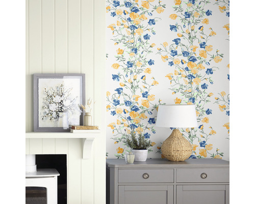 Decoratief interieur met behang met bloemmotief, commode, lamp en open haard.