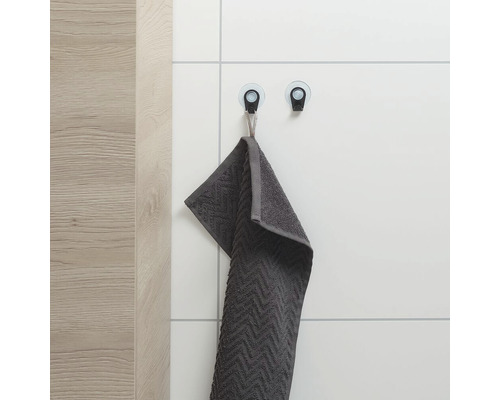 Grijze handdoek aan twee zuignaphaken aan de muur