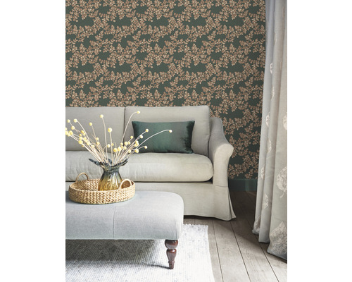 Woonkamer met groen bladerbehang, bank en voetenbank