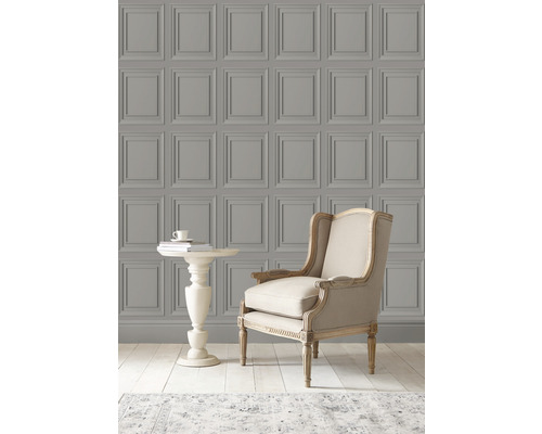 Scene met een wandbekleding met cassettepatroon, een fauteuil en een bijzettafel.