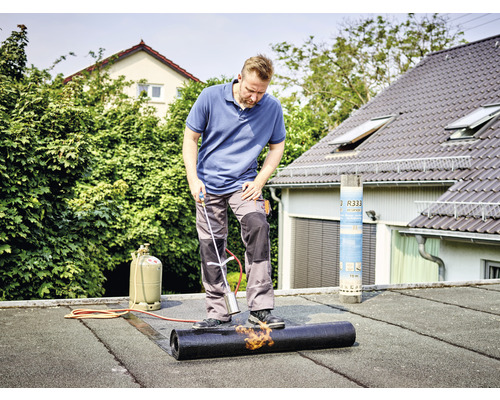 Ambachtsman last bitumenbaan op een plat dak met een brander