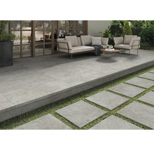 Terras met tegelvloer, zithoek en stapstenen in de tuin